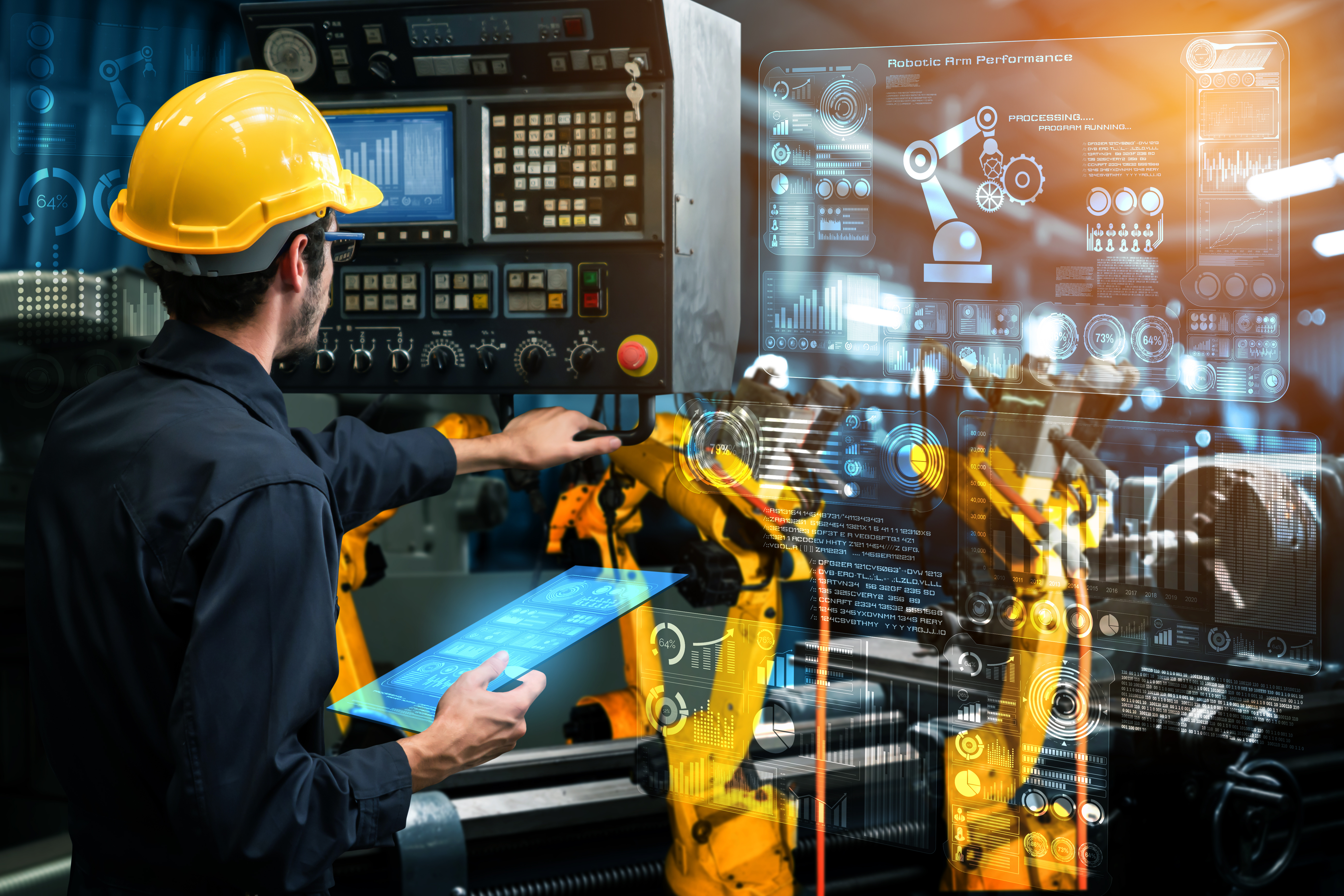 A worker in a hard hat operates industrial robot arms in a digital factory setting, interacting with advanced control panels and virtual data interfaces representing smart manufacturing technology.