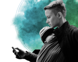 A parent holding a baby in a wrap while using a phone, set against a green background.