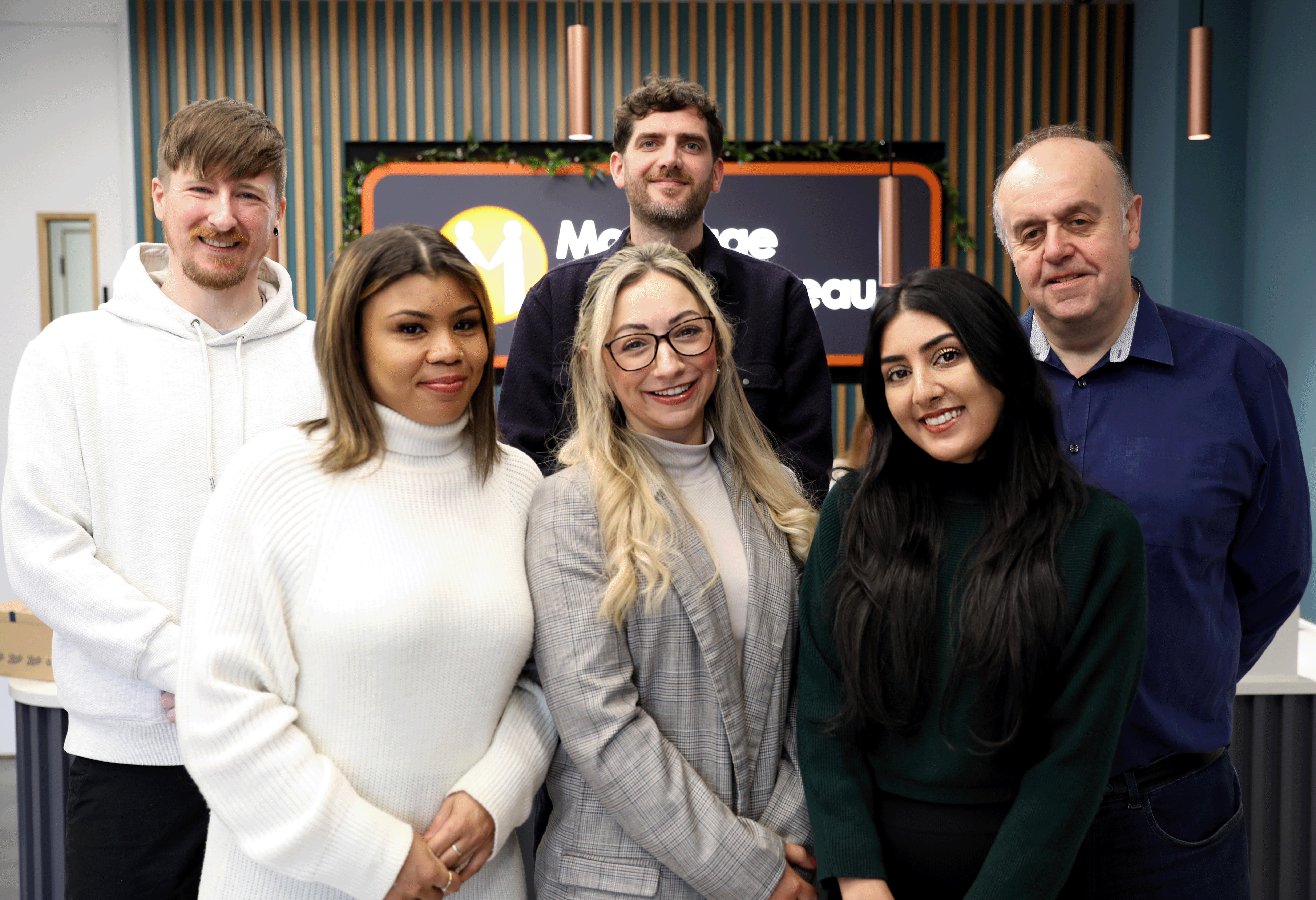 Group photo of six team members from the Mortgage Advice Bureau posing and smiling together in an office setting.
