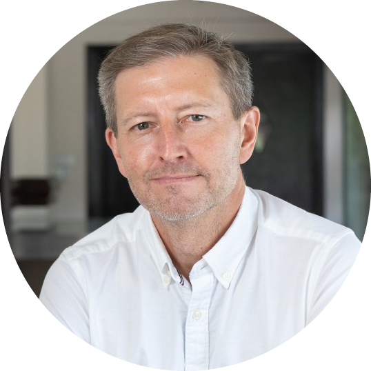 A portrait of a middle-aged man wearing a white shirt, posed indoors with a neutral expression.