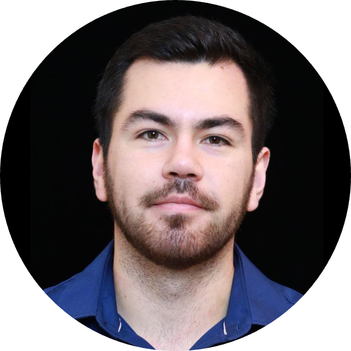 A professional headshot of a male with dark hair and beard, wearing a dark blue shirt, set against a dark background.