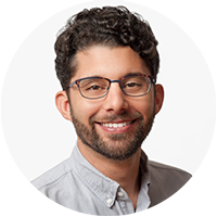 Professional headshot of a person with glasses and curly hair, smiling, used for the AWS Podcast 2023.