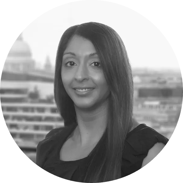 Black and white professional headshot photograph of a woman with long straight hair, smiling, with a cityscape background visible behind her.