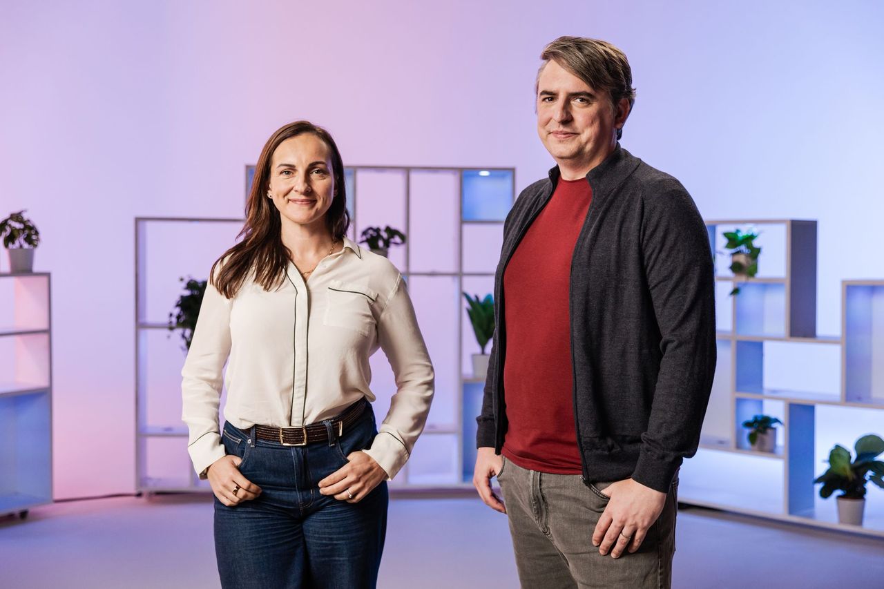 Woman and man standing in front of purple and pink gradient  background