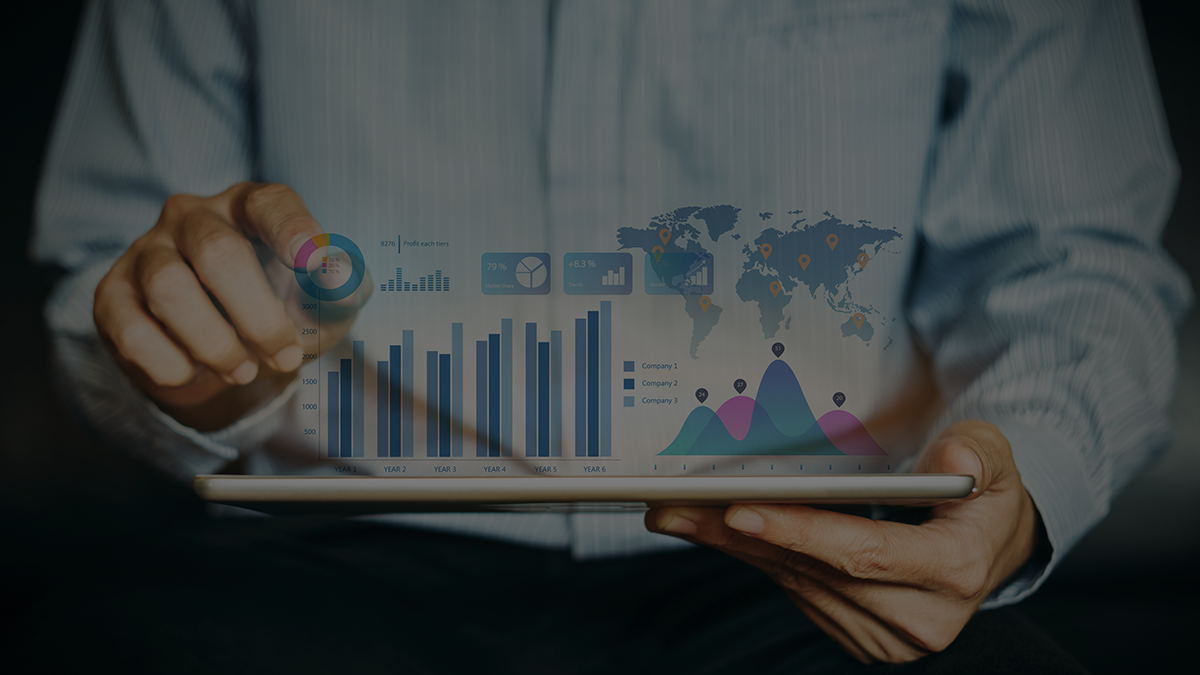 A person interacts with a digital tablet displaying a virtual data analytics dashboard with charts, graphs, and a world map visualization.