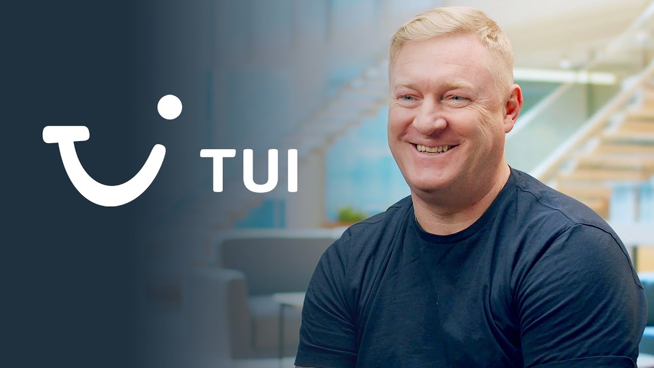 A person smiling and sitting in a modern office environment, with the TUI logo and text displayed prominently on the left side of the image.