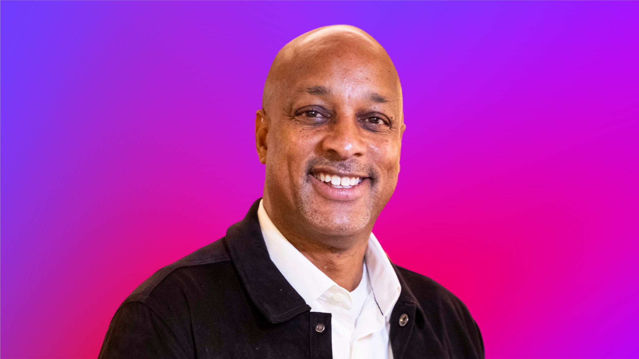 A person wearing a black jacket and white collared shirt against a vibrant purple-to-pink gradient background.