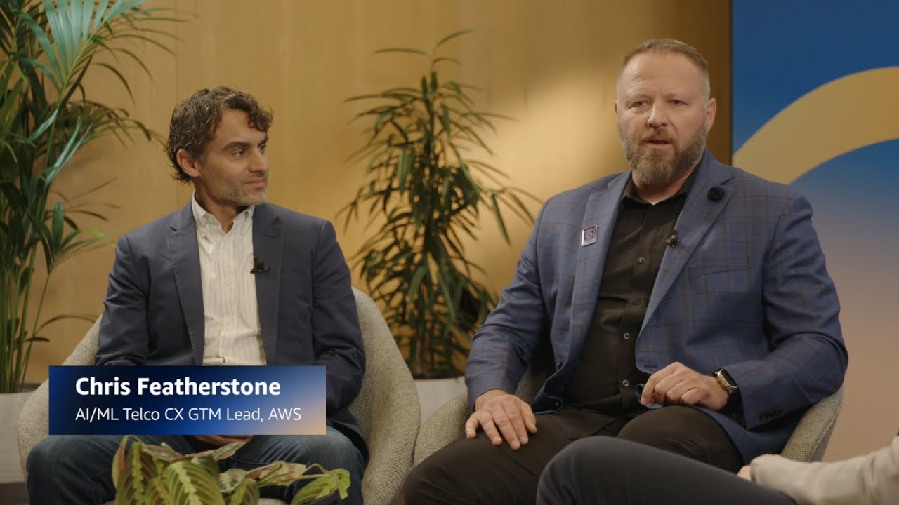 Thumbnail image for a YouTube video featuring Chris Featherstone, AI/ML Telco CX GTM Lead at AWS, during a discussion about artificial intelligence and machine learning in telecommunications. Two people in business attire are seated and engaged in conversation in a modern, plant-filled setting.