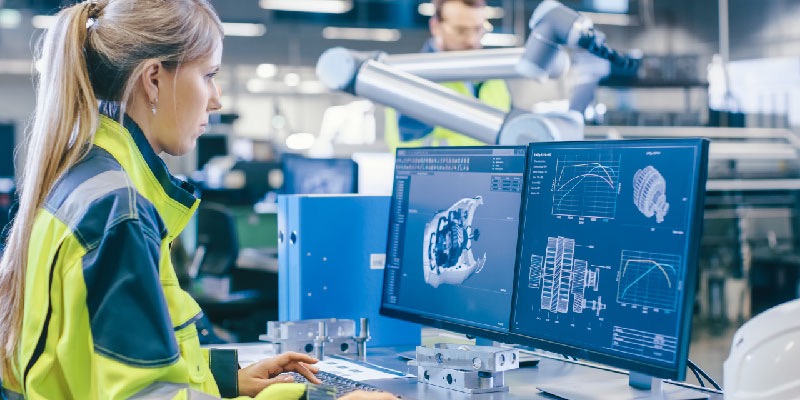 An engineer at a workstation uses advanced generative AI-powered CAD software to design mechanical components in a modern manufacturing facility.