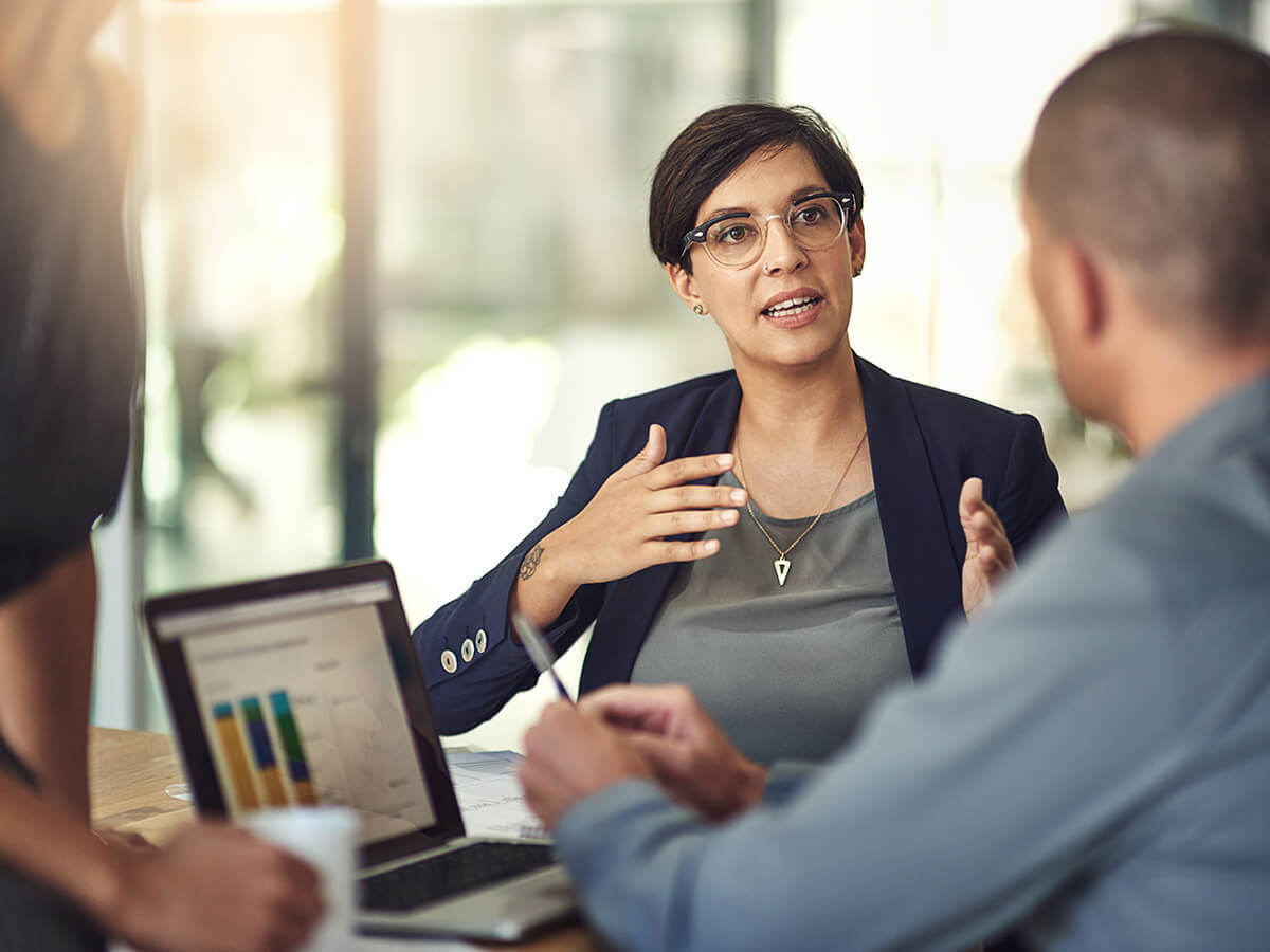 A salesperson presents data on a laptop to a colleague in a meeting