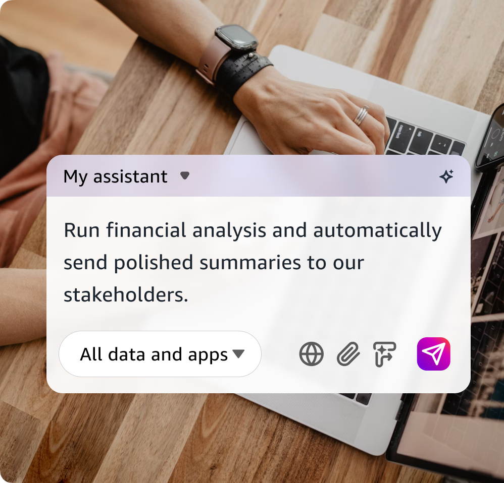 Overhead photo of a person wearing a smartwatch and ring typing on a laptop at a wooden table, with a smartphone nearby. Overlaid is an AI assistant interface labeled "My assistant" containing the prompt "Run financial analysis and automatically send polished summaries to our stakeholders," an "All data and apps" dropdown, and icons for web, attachments, and sending