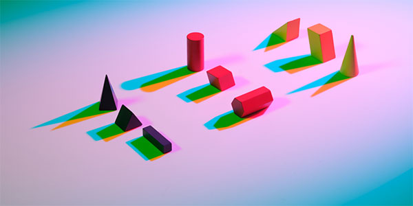 Assorted geometric shapes casting multicolored shadows on a surface with abstract lighting. Represents concepts in artificial intelligence, machine learning, and data modeling.