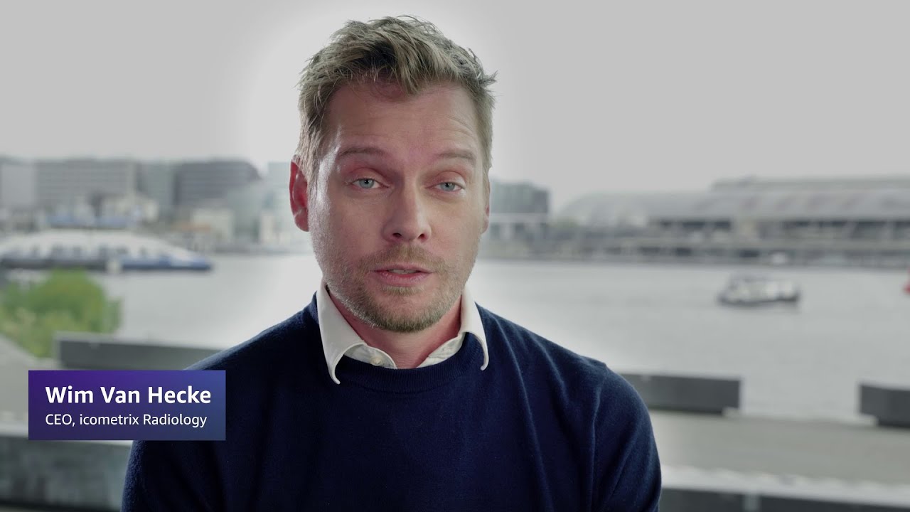 Wim Van Hecke, CEO of icometrix Radiology, with a waterfront cityscape in the background.