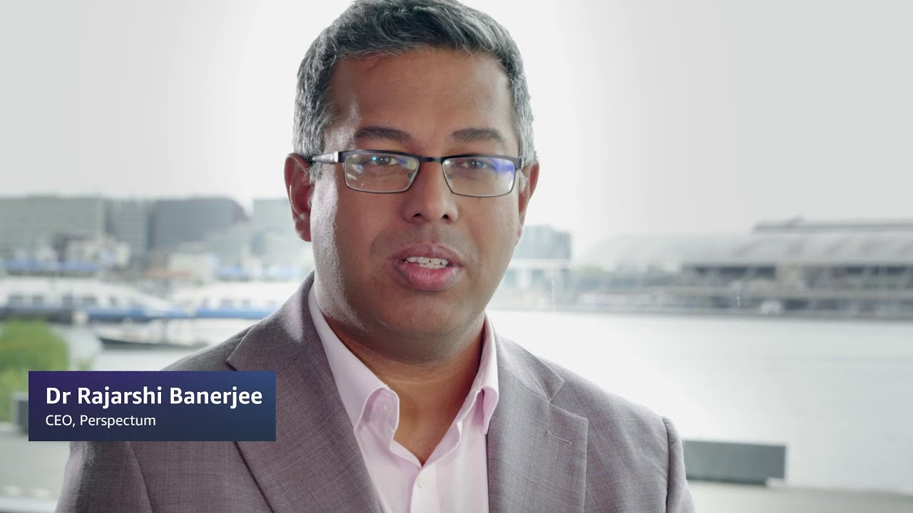 Dr. Rajarshi Banerjee, CEO of Perspectum, with a waterfront and urban buildings in the background.