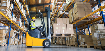 Worker operating a yellow forklift in a warehouse filled with shelves of boxes.