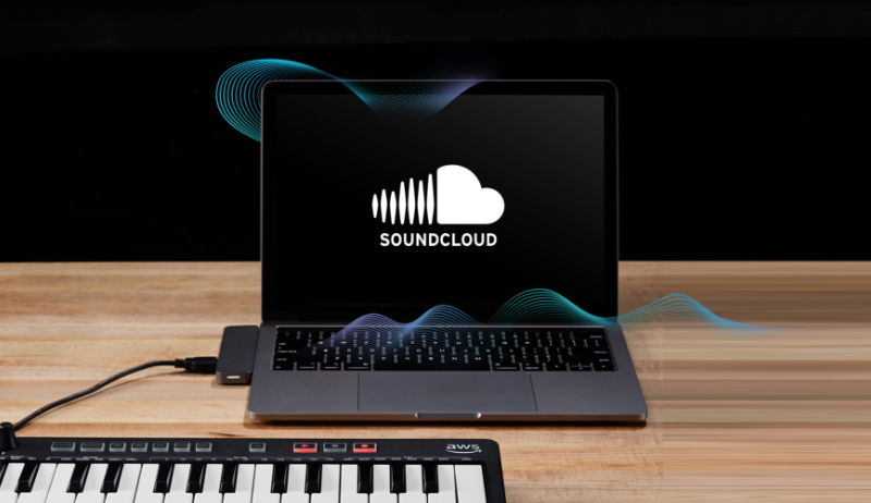 A laptop displaying the SoundCloud logo sits on a wooden table, connected to a MIDI keyboard with AWS branding. Abstract audio waveforms flow between the devices, emphasizing music technology and cloud integration.