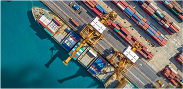 Aerial view of a busy shipping port with cargo containers, cranes, and docked ships.