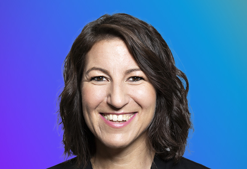 Dark brown wavy hair against a gradient blue and purple background.