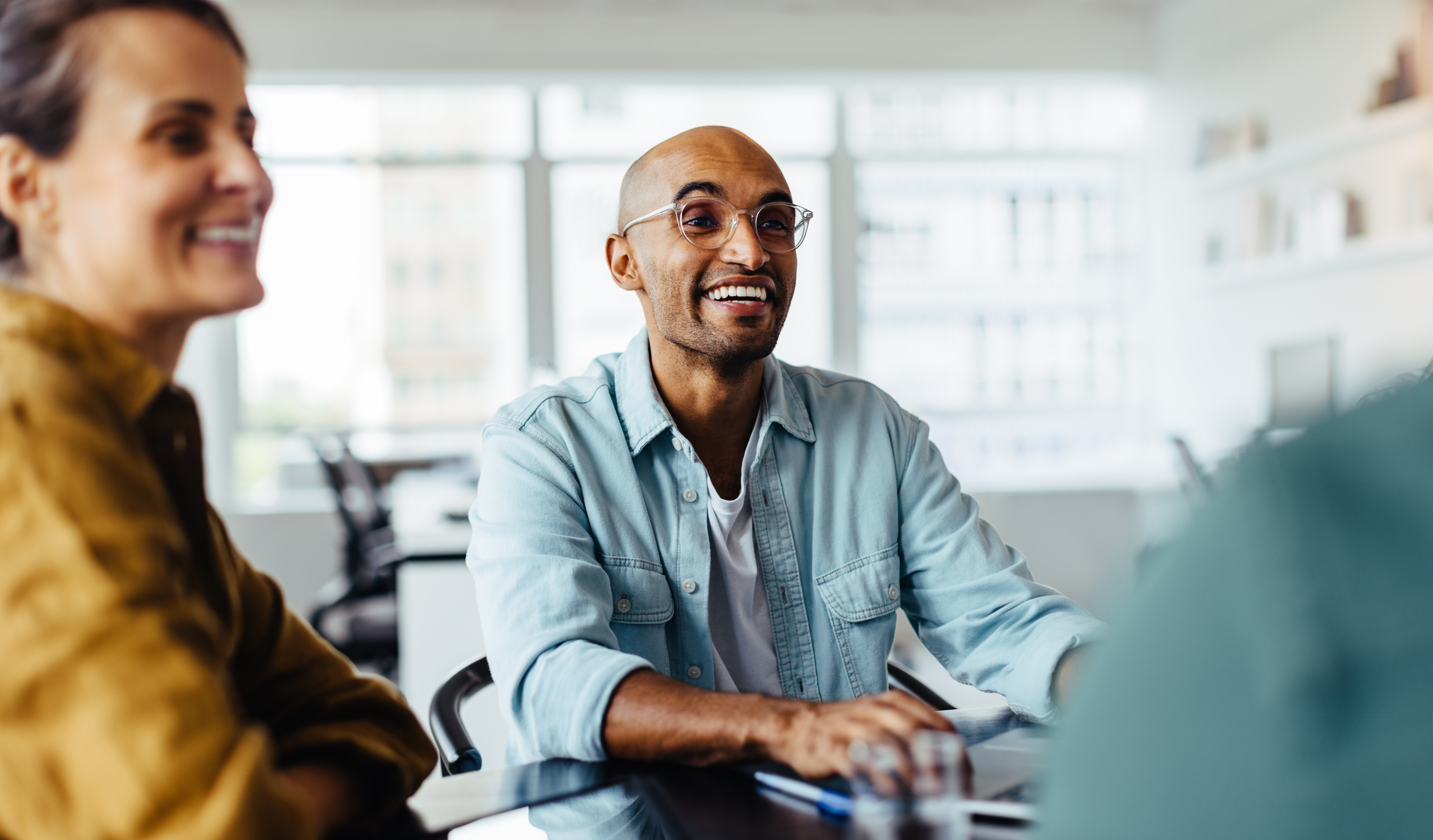 Business man having a meeting with his team in an office. Happy young man sitting around a table and discussing with his colleagues.