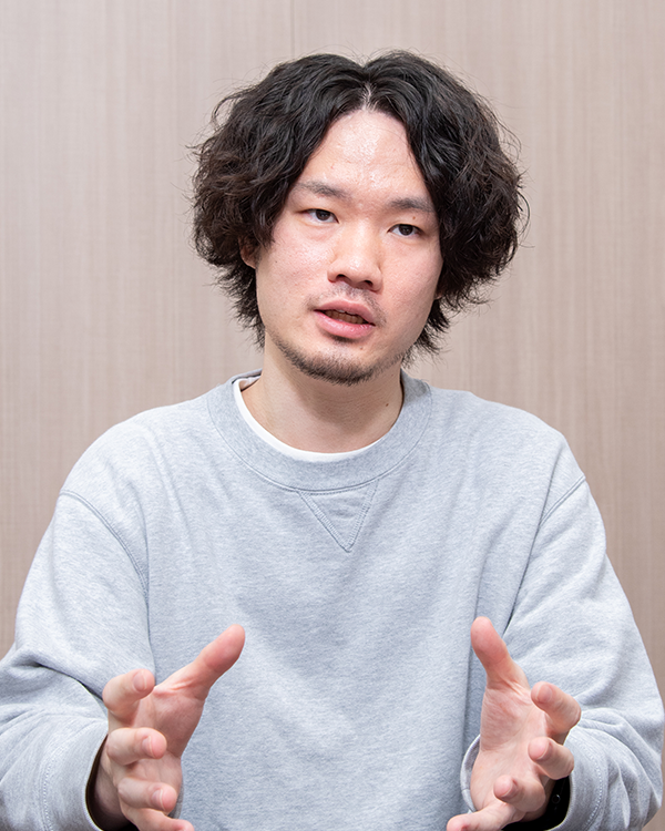 Man in grey sweatshirt talking and gesturing with hands