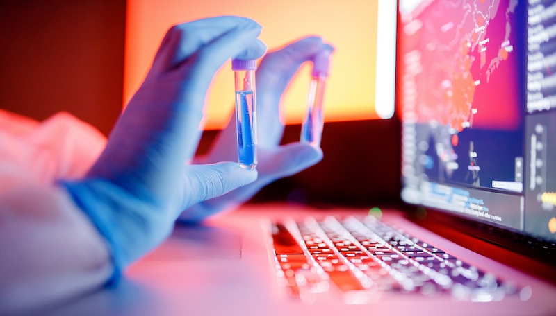 Nurse hold blood test tube in white hazmat protective suit in laboratory computer. Concept study antidote against epidemic.