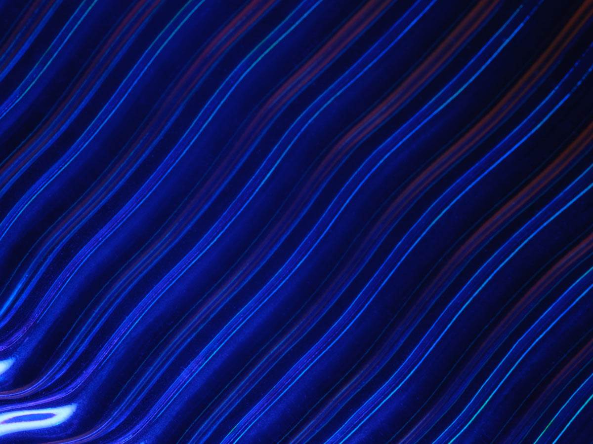 An abstract background featuring flowing blue wavy lines with light effects, suitable for analytics or technology themes.