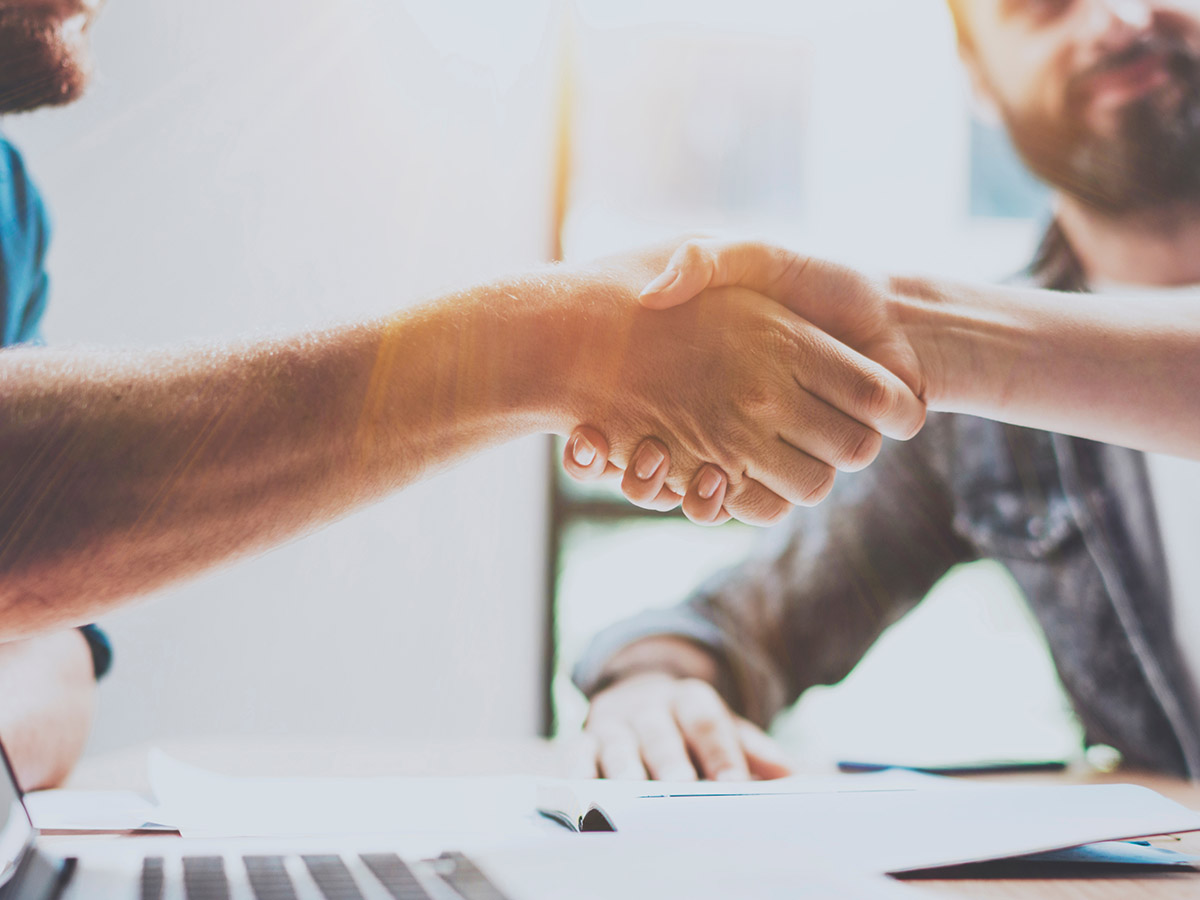 Two people shaking hands in an office setting, symbolizing a successful business partnership or agreement.