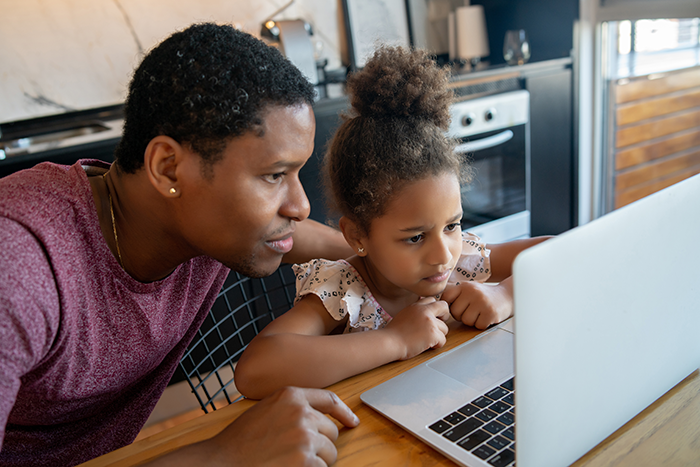 Father helping and supporting his daughter with online school while staying at home. New normal lifestyle concept.