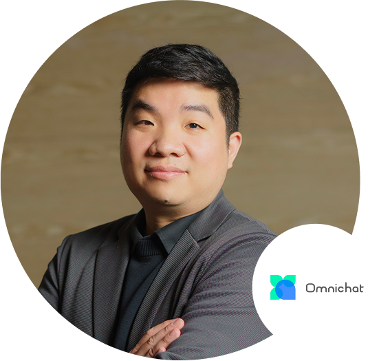 A business portrait of a man in a suit with folded arms, featuring the Omnichat logo in the foreground. Suitable for business application or professional branding.