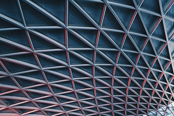 A modern architectural geometric ceiling structure with intersecting beams and a grid pattern, photographed from below.