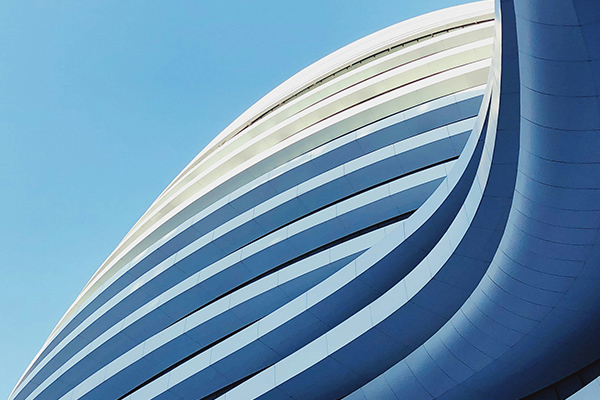 A photograph of a modern building with curved architectural lines set against a clear blue sky.