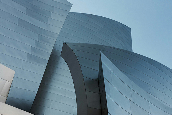 A modern building featuring curved metal architectural elements and a sleek, contemporary design against a clear sky.