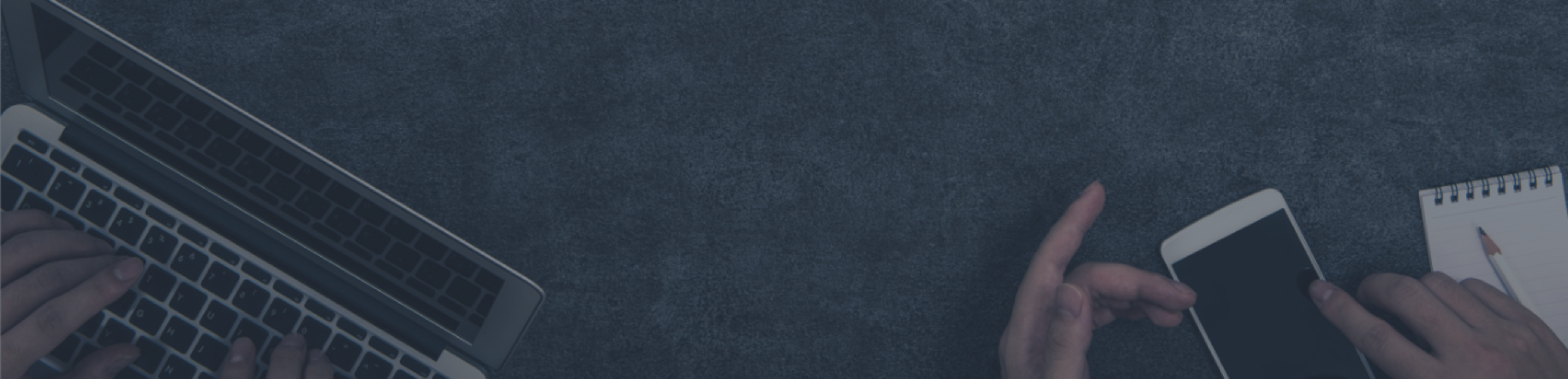 Hands using a laptop, smartphone, and notepad on a dark textured background. Technology and communication workspace concept.