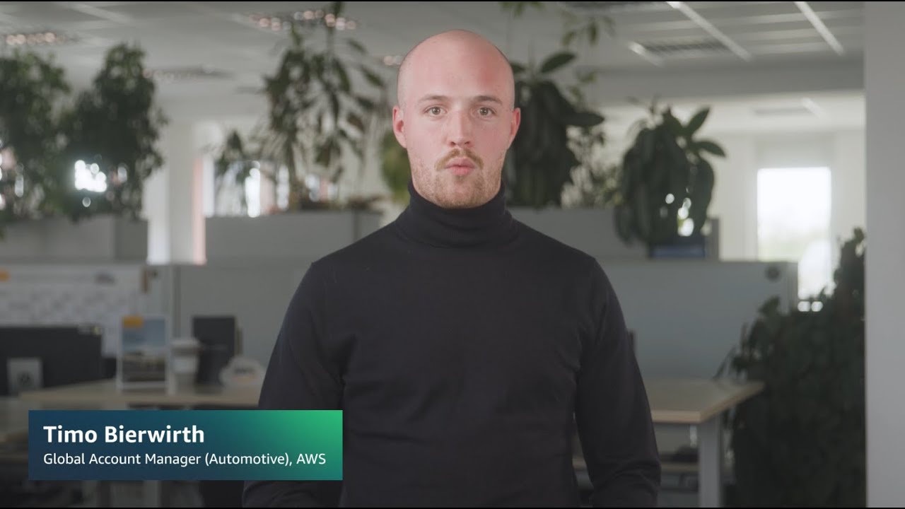 A YouTube thumbnail image showing a person in a black turtleneck standing in an office environment, with the text 'Timo Bierwirth, Global Account Manager (Automotive), AWS' displayed in the lower third.