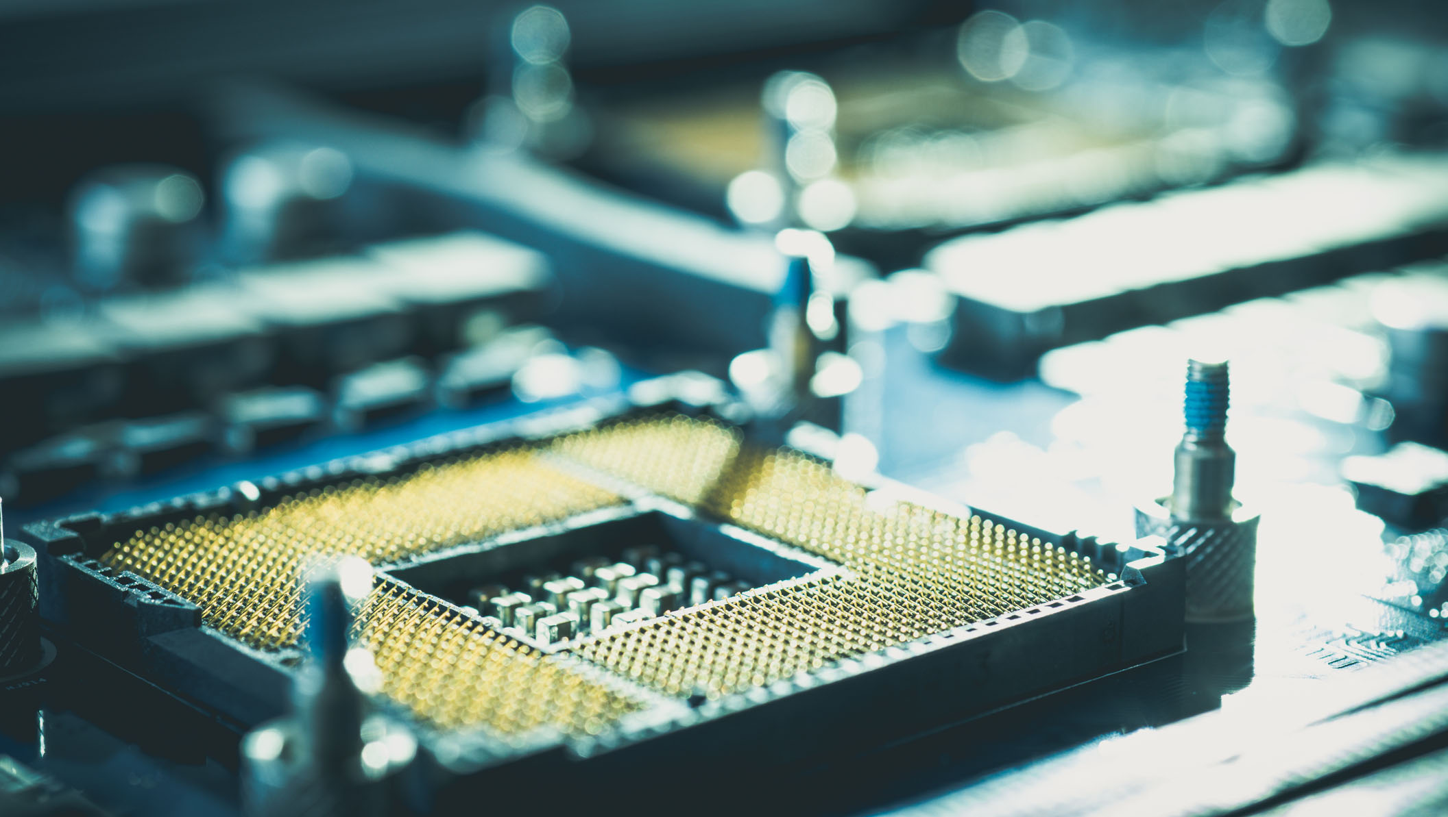 Closeup view of an electronic circuit board showing a CPU socket with gold pins, representing modern computer technology and hardware architecture.