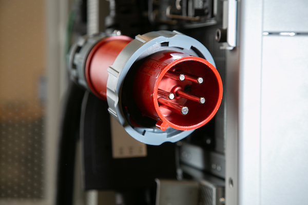 Close-up of a red industrial power plug connected to equipment.