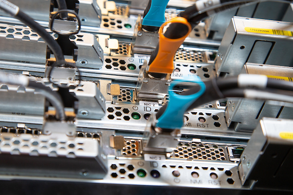 Close-up of server hardware with network cables connected to ports, featuring orange and blue cable connectors.