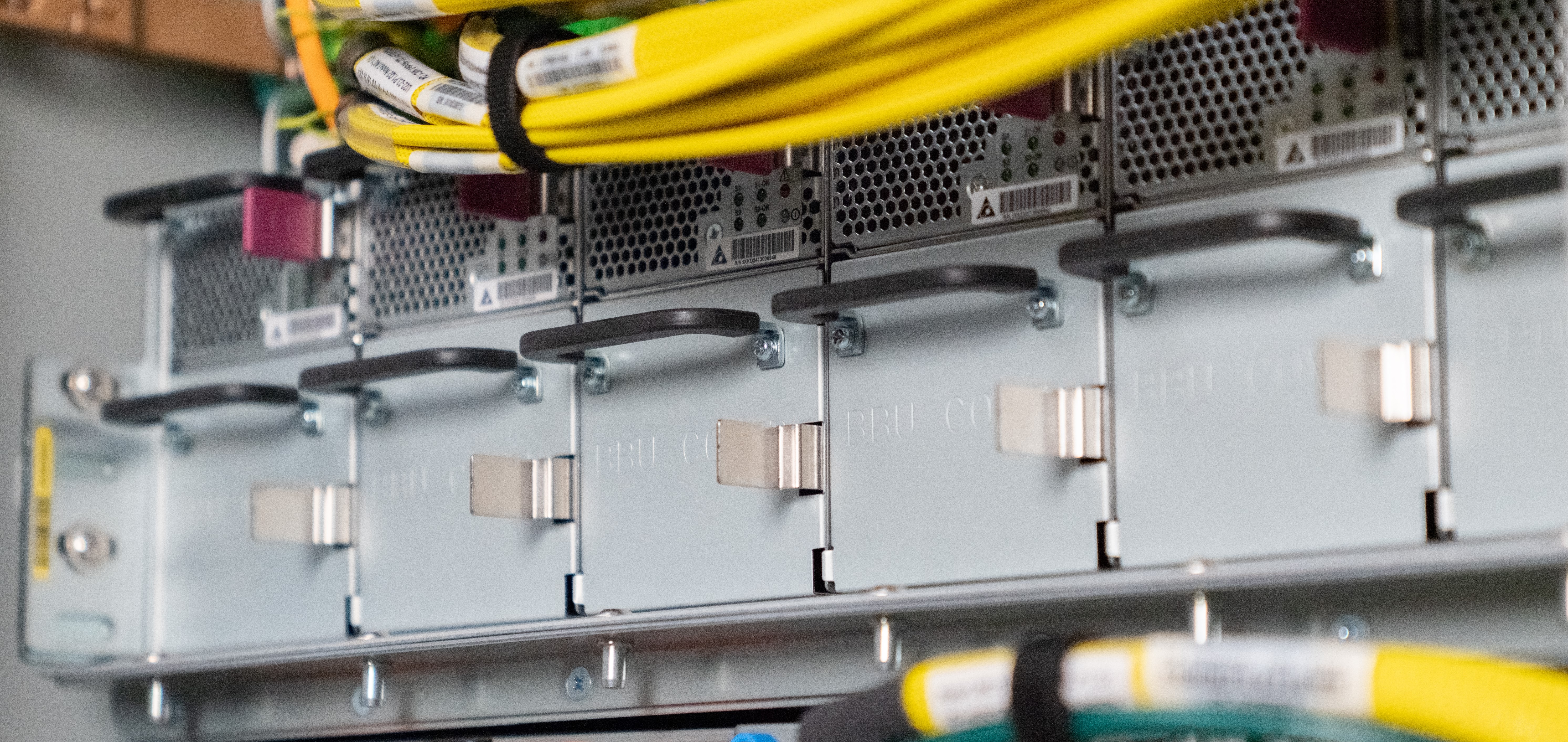 Close-up of server hardware with yellow and green cables connected to metal components.