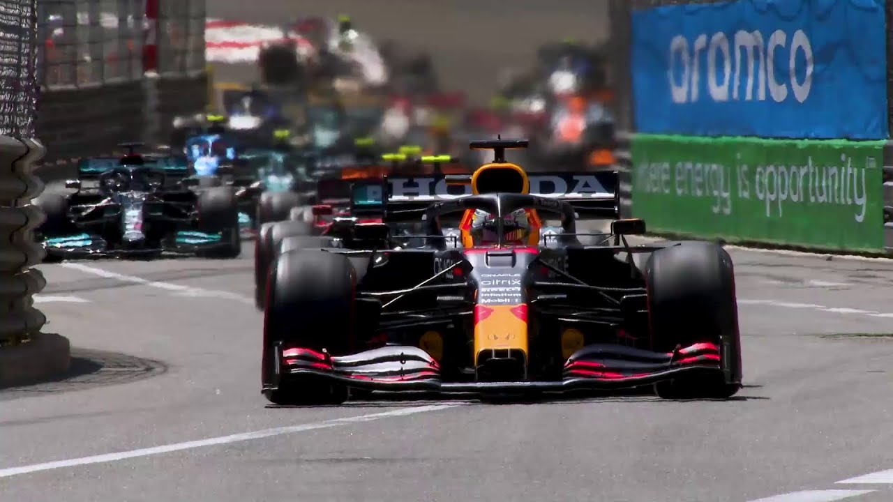 Red Bull Formula 1 car leading a race on a narrow track, followed closely by other cars.