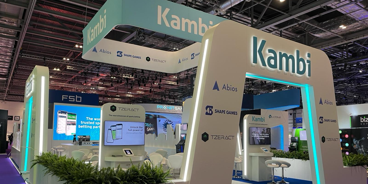 Kambi exhibition booth at a trade show, featuring illuminated signage, partner logos, and digital displays promoting sports betting solutions.