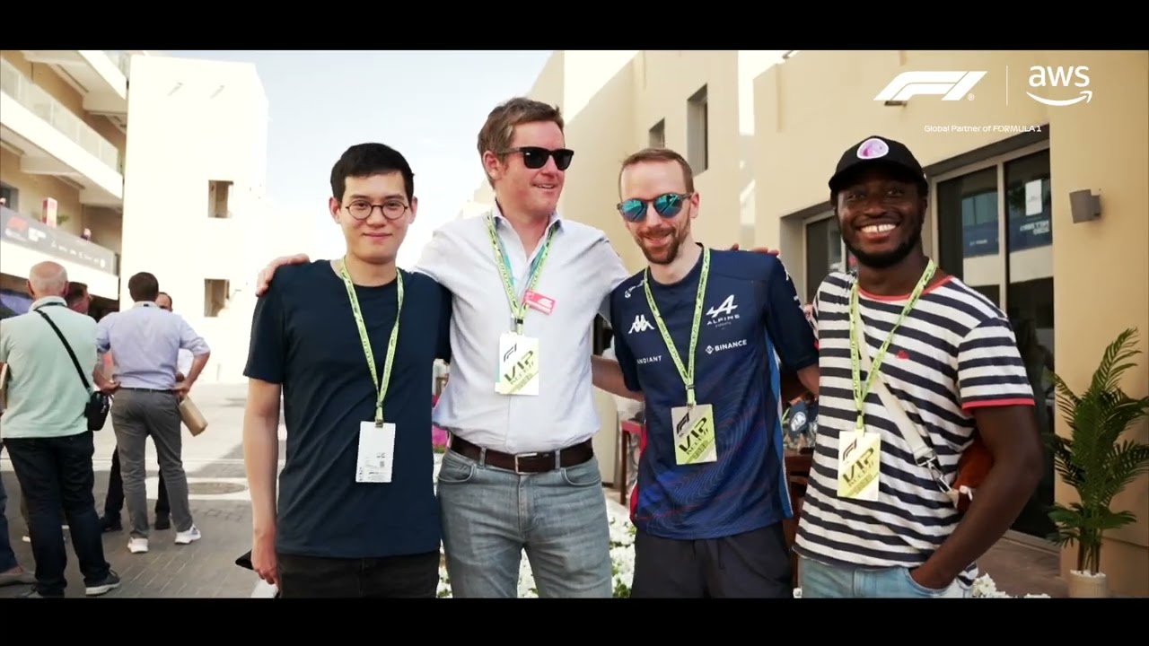 Group of people wearing VIP passes at a Formula 1 event, standing outdoors near modern buildings.