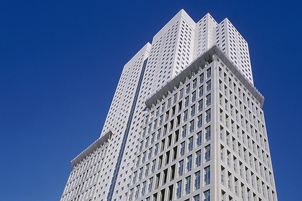 A tall, modern skyscraper with a grid-like facade against a clear blue sky.