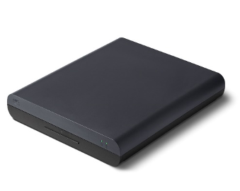 The image shows the AWS Panorama Appliance, a compact black device, in the initial stage of unboxing. The device is positioned upright on a white background.