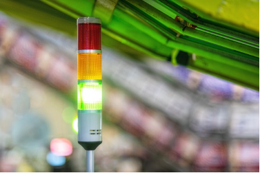 An industrial safety signal tower light displaying green, yellow, and red lights, commonly used in manufacturing or production environments to indicate equipment or process status.