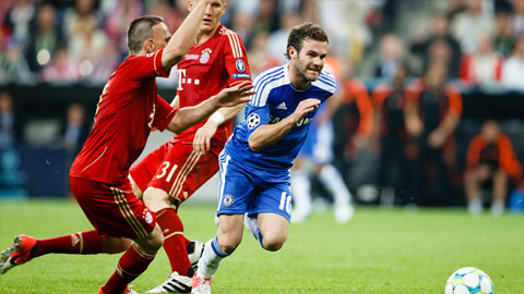 A soccer player in a red jersey attempts to tackle a player in a blue jersey during a match.