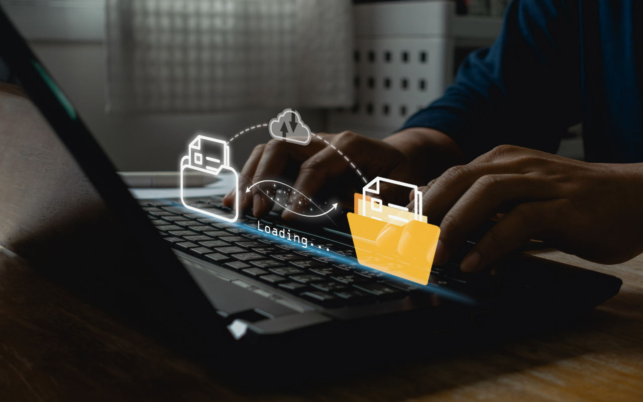 A person typing on a laptop keyboard with an overlay illustration representing data transfer between folders and the cloud, symbolizing cloud migration and data loading processes.