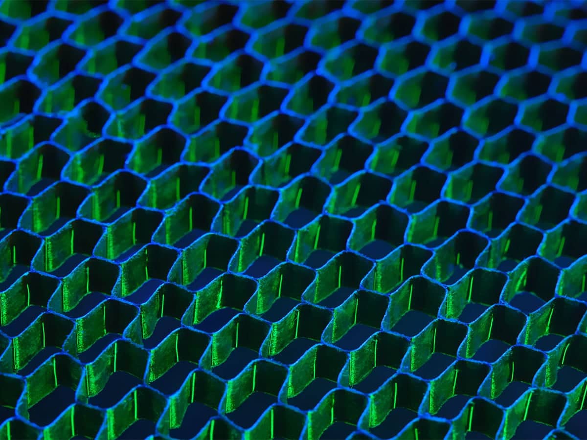 Close-up image of an abstract hexagonal grid pattern with blue and green lighting, representing concept of networking or connectivity.