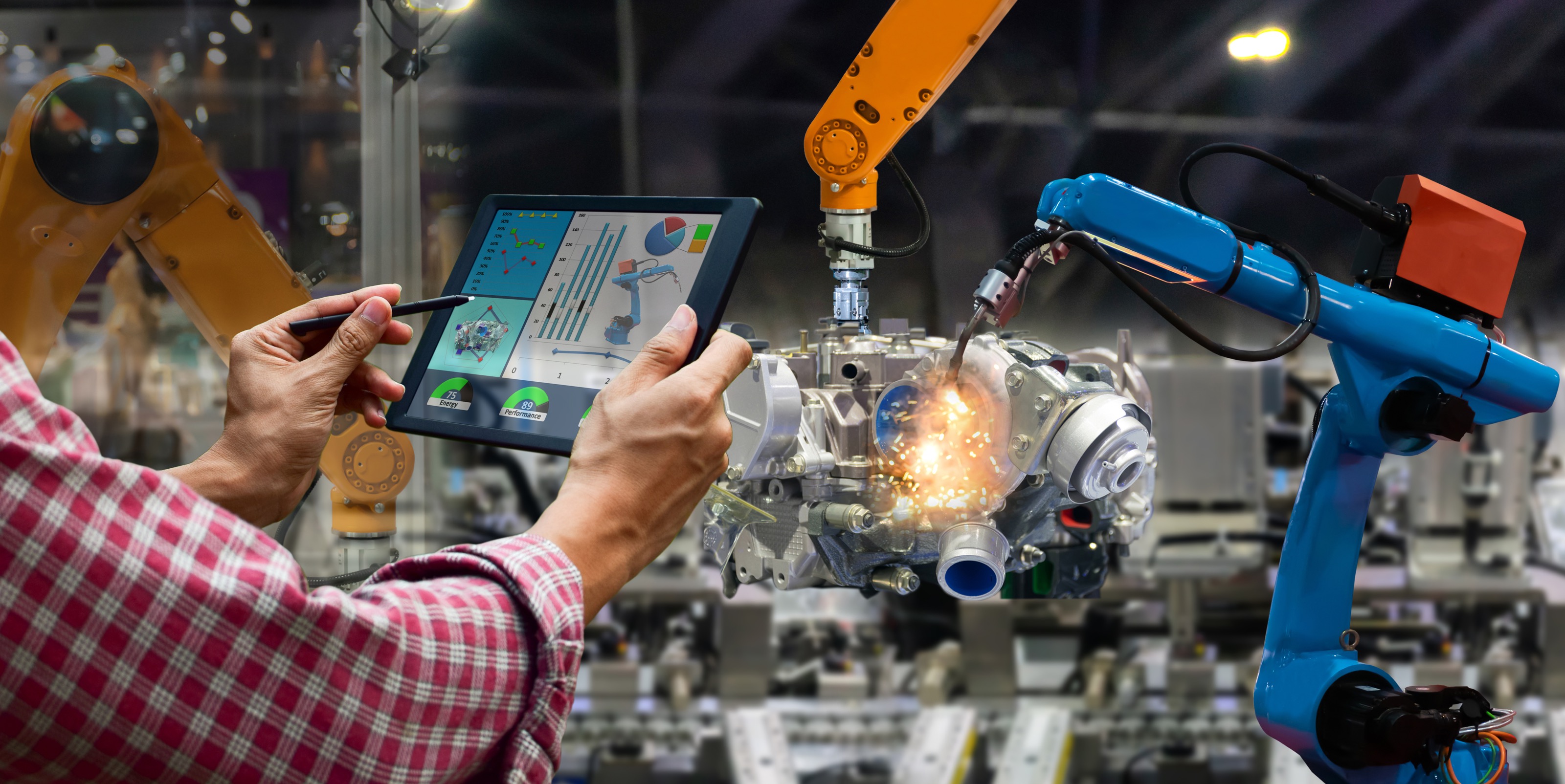 A person holding a tablet with data and graphs, monitoring robotic arms assembling a mechanical part with sparks flying.