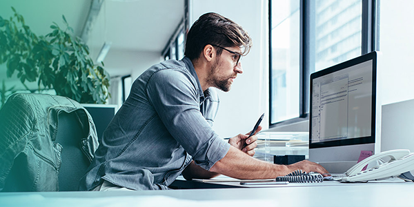 A compliance professional working at a desk with a computer, representing AWS security, identity, and compliance.