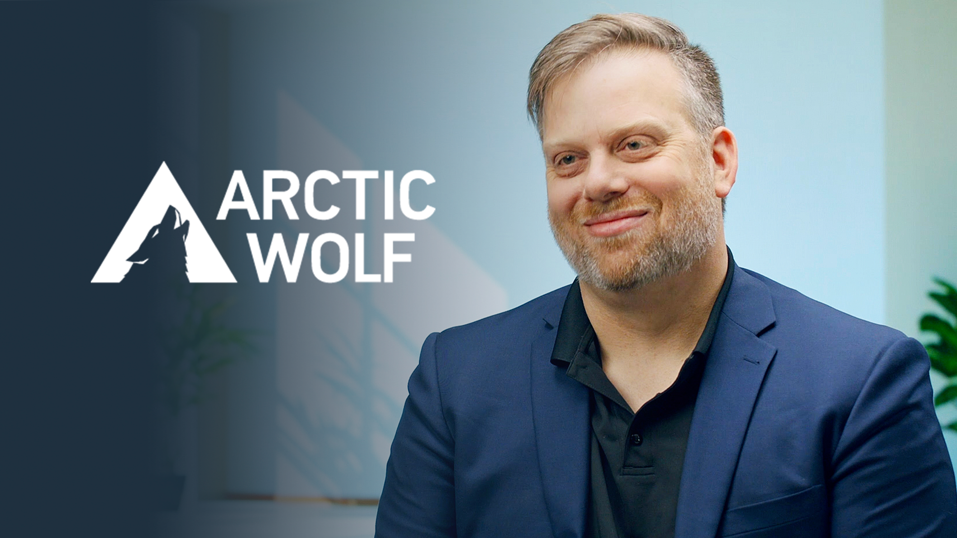 A man in a suit sits for an interview next to the Arctic Wolf logo at AWS re:Invent 2023.
